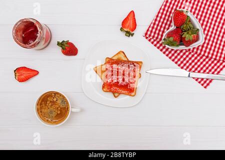 Toast mit Erdbeermarmelade, Erdbeeren und Kaffee auf dem weißen Tisch Stockfoto