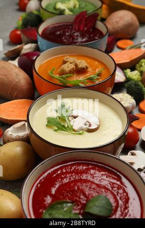 Gemüsesuppen und Zutaten auf grauem Tisch. Gesunde Ernährung Stockfoto