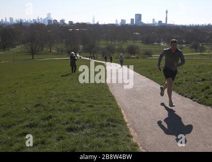 Die Skyline von London liegt in der Ferne hinter den Besuchern von Primsrose Hill, London. Stockfoto