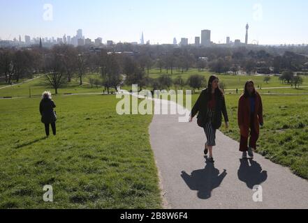 Die Skyline von London liegt in der Ferne hinter den Besuchern von Primrose Hill, London. Premierminister Boris Johnson sagte, die Regierung sei bereit, härtere Einschränkungen zu verhängen, um die Ausbreitung des Coronavirus einzudämmen, wenn die Menschen nicht den Leitlinien für soziale Distanzierungen folgen. Stockfoto