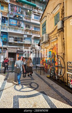 Touristen, die auf der schmalen gepflasterten Straße im historischen Zentrum spazieren gehen. Macau, China. Stockfoto