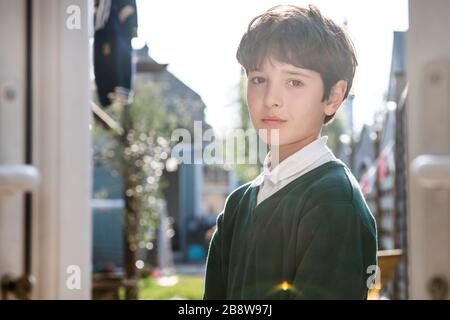 Porträt des Jungen mit braunem Haar mit grünem Pullover, im Freien stehend, mit Blick auf die Kamera. Stockfoto