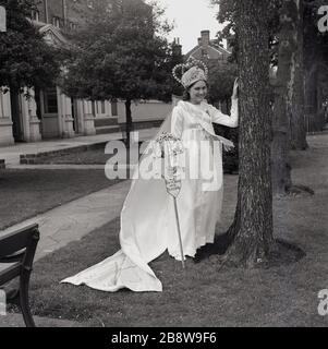 1960er Jahre, historisch, draußen stehend, die aufgeregte und neu krönte Londoner May Queen, ein junges Mädchen im Teenager-Alter, das ihren Gown und ihre Tiara, Lewisham, South East London, England, Großbritannien trägt. Stockfoto