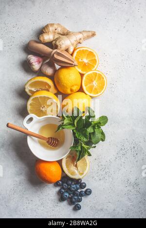 Gesunde Inhaltsstoffe für Immunität und Grippe-Schutz. Zitrusfrüchte, Ingwer, Honig, Blaubeeren und Minze auf weißem Hintergrund, Gesundheitskonzept. Stockfoto