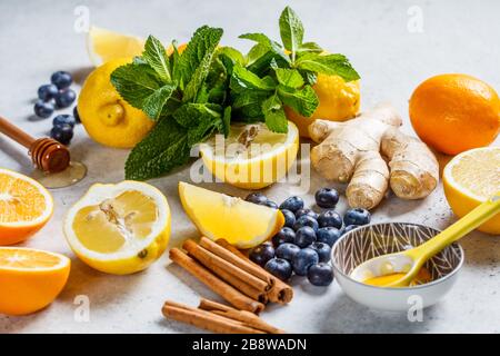 Gesunde Inhaltsstoffe für Immunität und Grippe-Schutz. Zitrusfrüchte, Ingwer, Honig, Blaubeeren und Minze auf weißem Hintergrund, Gesundheitskonzept. Stockfoto
