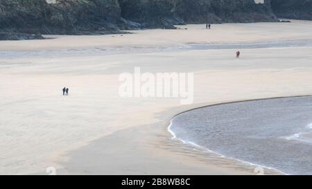 Ein Panoramablick auf die fernen Figuren der Wanderer auf dem preisgekrönten Crantock Beach bei Ebbe in Newquay in Cornwall. Stockfoto