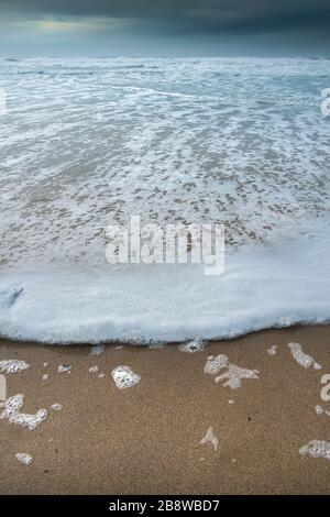 Eine sanfte Welle, die auf einer Flut an einem kalt kühlt windigen Fistral Beach in Newquay in Cornwall fliesst. Stockfoto