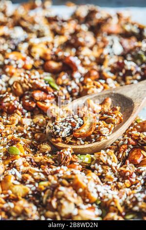 Knusprige hausgemachte Granola mit Nüssen, Trockenfrüchten und Sesamsamen auf einem Backblech. Stockfoto