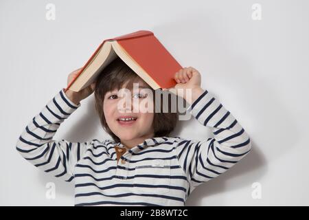 Vorschulter mit rotem Buch auf dem Kopf . Stockfoto