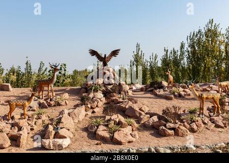 Katta Turk, Usbekistan - 18. Oktober 2019: Statue von sika-hirschen und Adlern auf einem Berg von Steinen auf der Seite der Straße im Distrikt Dangara. Stockfoto