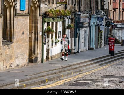 Edinburgh, Schottland, Großbritannien. März 2020. Leere Straßen während der Pandemie von Covid-19 Coronavirus in der Hauptstadt, da die Botschaft, zu Hause zu bleiben, die sozialen Distanzierungsmaßnahmen zu beachten scheint, trotz des schönen Sonnenscheins im Frühling Wirkung zu zeigen. Der Lawnmarket an der Royal Mile ist verlassen, bis auf einen Mann, der in voller Militäruniform zur Burg geht Stockfoto