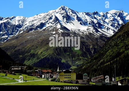 Plangeross, Österreich - 23. Juni 2016: Kleines Dorf in Pitztal mit verschneiten Tiroler Alpen im Hintergrund, bevorzugte Gegend für Skifahren und Wandern Stockfoto