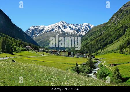 Plangeross, Österreich - 23. Juni 2016: Kleines Dorf in Pitztal mit verschneiten Tiroler Alpen im Hintergrund, bevorzugte Gegend für Skifahren und Wandern Stockfoto