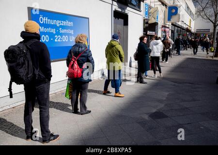 Berlin, Deutschland. März 2020. Die Leute stehen vor einem Supermarkt in Berlin-Wilmersdorf. Um die Ausbreitung des Coronavirus zu verlangsamen, hat die Bundesregierung das öffentliche Leben erheblich eingeschränkt. Credit: Christoph Soeder / dpa / Alamy Live News Stockfoto