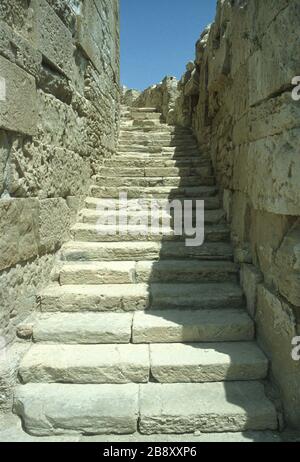 Überreste des spektakulären griechischen Theaters auf der Klippe in Kourion, Episkopi, Limassol, Zypern. Steinerne Sitzmöbel in kreisförmigen Reihen im Auditorium und die Stufen, die für jedes Level verwendet wurden. Blauer Himmel im Hintergrund. Stockfoto