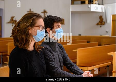 Ein junges Paar in Gesichtsmasken betet während der COVID-19-Pandemie in einer Kirche. Bratislava, Slowakei. Stockfoto