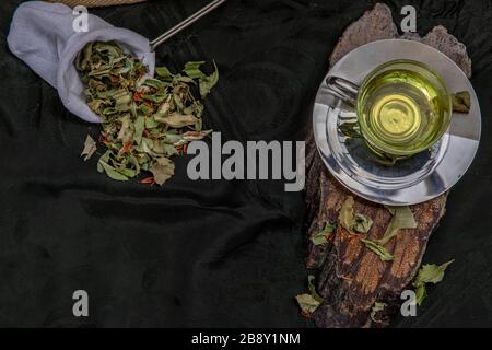 Eine Tasse Pandanblatt-Tee, indische Marschen Flabane Pflanzen Blätter mit Safflower getrocknet (Saffron-Ersatz) auf dunklem Hintergrund. Thailändische Kräuterpflanze und -Alt Stockfoto