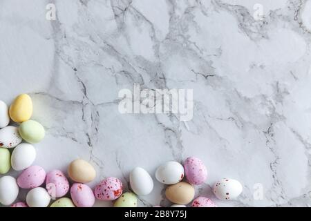 Frohe Ostern Konzept. Vorbereitung für den Urlaub. Ostern Eier in Pastellfarben Süßigkeiten Schokolade Bonbons auf trendige grauem Marmor Hintergrund. Einfache Minimalismus flach Ansicht von oben kopieren Raum Stockfoto