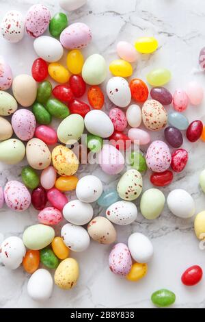 Frohe Ostern Konzept. Vorbereitung für den Urlaub. Ostern Süßigkeiten Schokolade Eier und fruchtgummi Bonbons auf trendige grauem Marmor Hintergrund. Einfache Minimalismus flach Ansicht von oben kopieren Raum Stockfoto