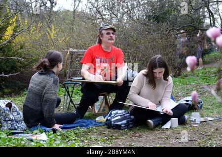 Malen in einem Park. Malerin gibt Zeichenunterricht für zwei Mädchen. Botanischer Garten von Fomin, Kiew, Ukraine Stockfoto