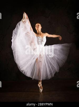 Schlanke Frau in einem weißen Korsett tutu tanzen Ballett. Studio-Aufnahmen vor dunklem Hintergrund, isolierte Bilder. Stockfoto