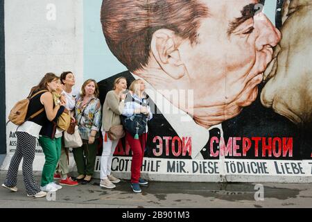 Touristen, die beim Wandgemälde "Brubel Kiss" von Dmitri Vrubel fotografieren. Berlin, Deutschland Stockfoto