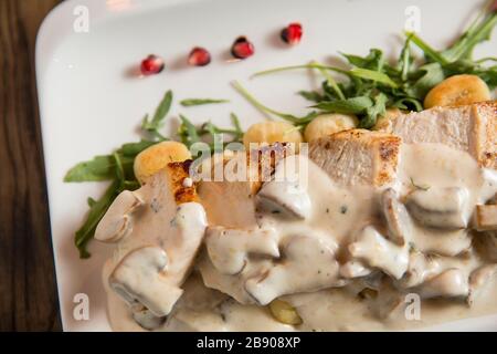 Huhn auf geriebenem Gnocchi in Sahnesauce aus Pilzen und Räucherkäse auf dem Tisch Stockfoto