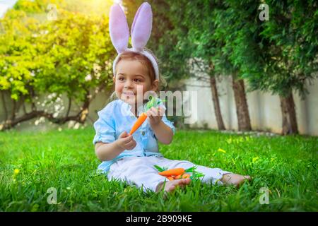 Kleiner Baby-Junge mit Freude an der Feier von Ostern, mit lustigen Funny-Ohren und einem sonnigen Tag auf dem Hinterhof, fröhlicher Frühlings-Urlaub Stockfoto