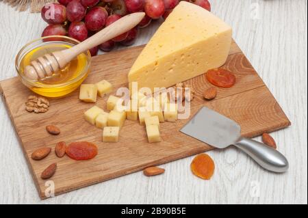 Auf einem Brett mit Honig, Trauben, getrockneten Aprikosen und Nüssen gewürfelt Stockfoto