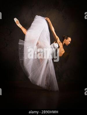 Schlanke Frau in einem weißen Korsett tutu tanzen Ballett. Studio-Aufnahmen vor dunklem Hintergrund, isolierte Bilder. Stockfoto