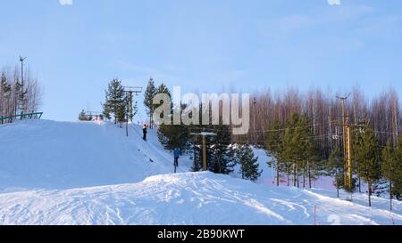 Skilifte dauern hellen Wintertag. Skifahrer und Snowboarder klettern mit einem Skilift auf den Berg Stockfoto