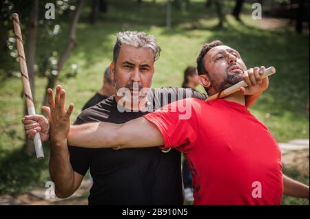 Filipino escrima arnis Instruktor und Student Practice Stick Fight Choke Techniken auf dem Kapap Martial Arts Seminar Stockfoto