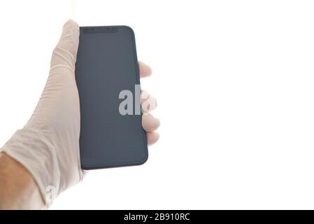 Protegido a mano con guantes de látex blancos para usar el teléfono inteligente como protección contra el Covid-19. Coronavirus, Virus y enfermedades Stockfoto