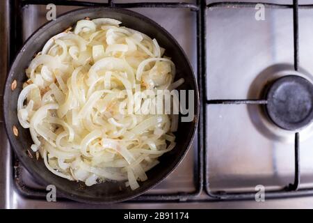 Zwiebeln in einer Bratpfanne kochen. Hausküche. Draufsicht. Stockfoto