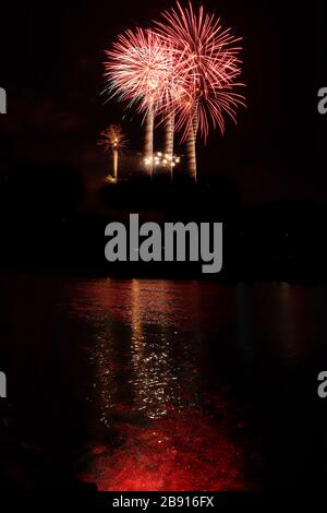 Rotes Feuerwerk über der Mosel mit Lichtreflexionen im Wasser, die bei einer jährlichen Veranstaltung in der Stadt Koblenz wie Flammen aussehen. Stockfoto