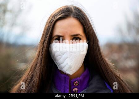 Junge Frau, die während der Epidemie des Coronavirus (COVID-19) eine schützende, chirurgische Gesichtsmaske trägt. Nahaufnahme im Hochformat mit mehreren Verwendungszweck Stockfoto