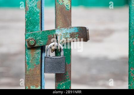 Geschlossener und verschlossener Türgrill mit silberfarbenem Vorhängeschloss. Ein Metallschloss an Scharnieren hängt in Nahaufnahme am Gitter. Sicherheitskonzept oder Verbot, Kopierraum für Ihren Stockfoto