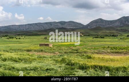Landschaft in der Nähe von Farooj mit kleinem Dorf in der Provinz Razavi Khorasan mit grünen Feldern und Moschee im Sommer im Iran. Stockfoto