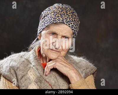 Porträt einer alten Frau auf dunklem Hintergrund. Menschen solchen Alters sind während Epidemien am anfälligsten Stockfoto