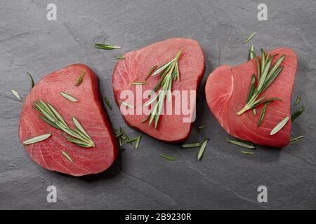 Rohes Thunfischsteak mit Rosmarin auf schwarzem Stein Stockfoto