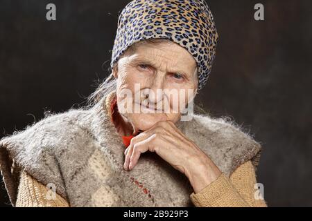 Nahaufnahme Porträt einer alten Frau mit nachdenklichen Blick auf dunklen Hintergrund. Menschen solchen Alters sind während Epidemien am anfälligsten. Stockfoto