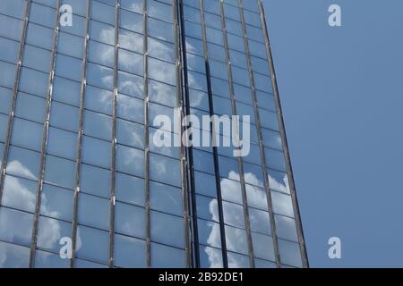 Wolken und blauer Himmel spiegelten sich auf Glasbaufenstern wider. Architektonischer Hintergrund. Stockfoto