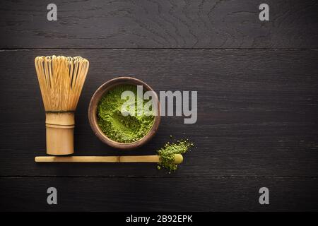 Matcha-Pulver. Organische grüne Matcha-Teezeremonie. Gesundes Getränk. Traditionelles japanisches Getränk auf schwarzem Holzhintergrund Stockfoto