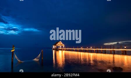 Nachtpier Blick auf das Meer beleuchtet mit Hängematte auf dem Wasser Stockfoto