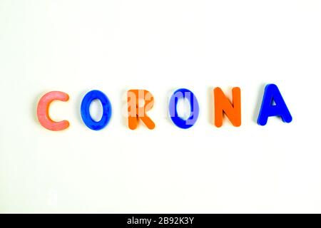 CORONA-WORT, das in verschiedenen farbigen Buchstabenblocks auf einem isolierten weißen Hintergrund geschrieben wurde Stockfoto