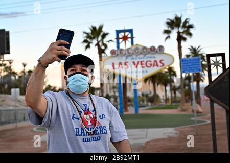 Las Vegas, Nevada, USA. März 2020. Eddie Sarinana aus Las Vegas, der eine schützende Gesichtsmaske trägt, nimmt am 23. März 2020 in Las Vegas, Nevada, ein selfie vor dem Willkommensschild in Las Vegas. Nevada Reg. Steve Sisolak ordnete an, bis zum 16. April unwesentliche Geschäfte im Staat zu schließen, um die Verbreitung des Virus zu bekämpfen. Die Weltgesundheitsorganisation erklärte das Coronavirus (COVID-19) am 11. März zu einer globalen Pandemie. Credit: David Becker/ZUMA Wire/Alamy Live News Stockfoto