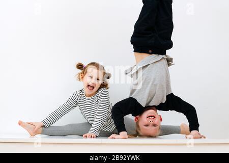 Bruder, der auf dem Kopf steht, und Schwester, die auf dem Garn sitzt Stockfoto