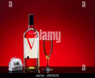 Eine Flasche Weißwein mit einem Glas Geschenkkarton auf rotem Hintergrund. Stockfoto