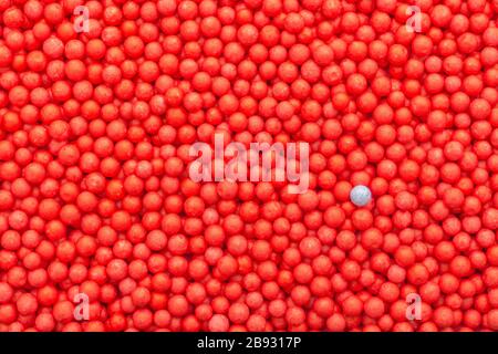 Farbige kleine rote und blaue Polystyrolkugeln. Konzeptionell für Covid-19 Selbstisolation, Krankheitsträger, infizierte Person, isoliert, in der Menge verloren Stockfoto