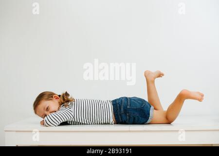 Mädchen, die auf dem Tisch liegen, lacht und verschlungen die Beine Stockfoto